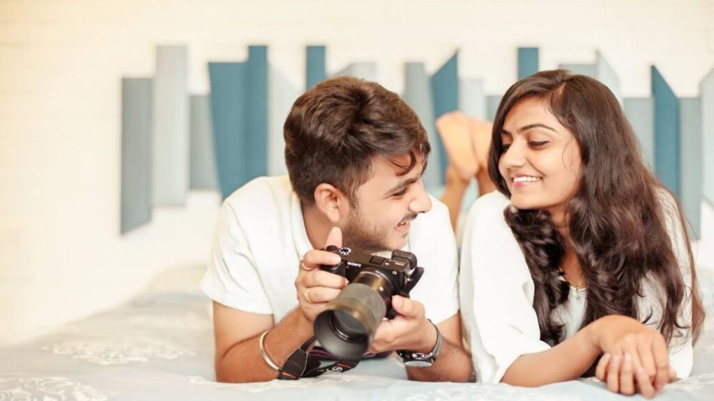 男女が寝転がりながら、見つめ合い会話をしている。男性はカメラを手にしている