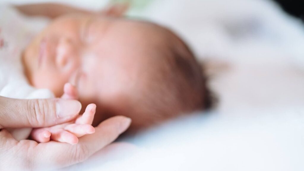 赤ちゃんの手を握っている大人の手