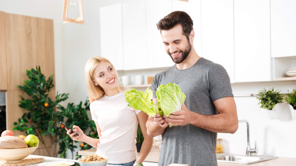キッチンで男女が料理をしている。
男性の手には野菜。